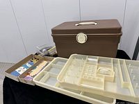 Overall view: brown plastic sewing case with interior cream tray and grouped supplies