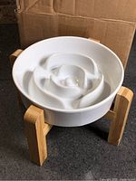 white ceramic slow feeder dog bowl on bamboo stand front view