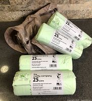 Six rolls of compostable food waste bags including four sealed The Caddy Company 25-L rolls and loose rolls