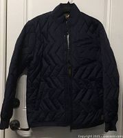 Front view of the navy quilted puffer coat hanging on door