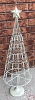 Full view of silver metal wire Christmas tree with star topper and base