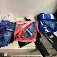 Three folded XL microfiber beach towels showing patterns and mesh storage bags