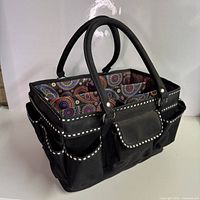 Front view of black fabric organizer caddy with white trim and paisley interior
