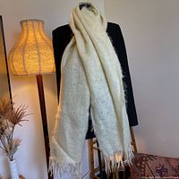 Full view of cream mohair scarf draped on mannequin beside lamp