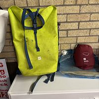 Front view of MEC Slog 35L dry pack with water container and pillow beside it