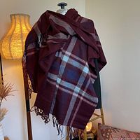 Full view of burgundy plaid wool scarf draped to show size and fringe