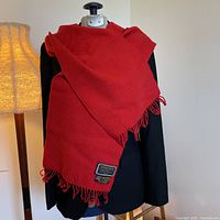 Full view of red scarf draped on mannequin over black jacket