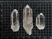 Three quartz points on measurement grid showing sizes