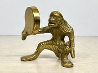 Right side view of brass monkey figurine holding mirror