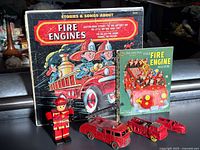 Group shot of record, book, three toy fire trucks and firefighter figure