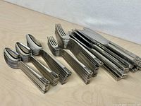 Stacked teaspoons, forks, knives showing handle pattern