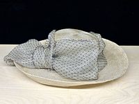 Full view of straw hat showing brim and lace bow