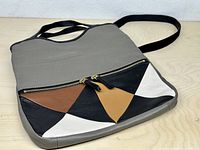 Front view showing gray pebbled leather body and color-block triangular front zip pocket