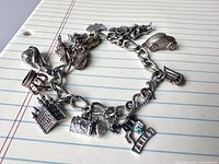 Full view of sterling charm bracelet with all charms visible on notepaper background