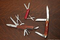 Three pocket knives laid open showing all tools