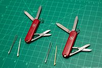 Two Victorinox Classic SD multi-tools open with accessories laid out