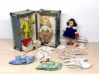 Overview of both dolls, trunk, clothing laid out
