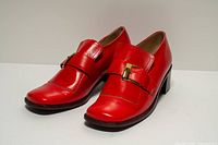 Three-quarter front view of both shoes showing uppers and buckle detail