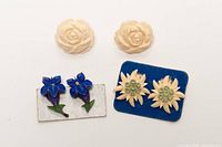 Overview of three earring pairs: cream roses, blue lilies on card, cream edelweiss on blue backing