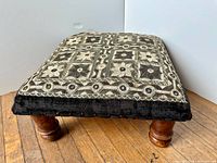 Angled view showing entire stool, wooden legs and embroidered cushion