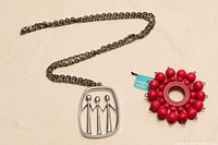 Both jewellery pieces together: pendant on chain and red bead brooch