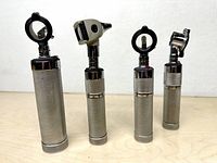 Four Welch Allyn power handles with various diagnostic heads standing upright