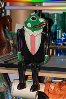 Front view of seated wooden frog figurine in tuxedo