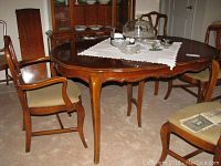 Dining table and chairs arranged in room, showing table top, two arm chairs and two side chairs