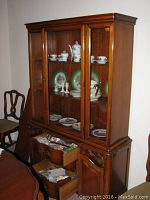 Front view of the wooden JB Van Sciver hutch showing glass doors filled with china and decorative plates. Lower drawers are partially open.
