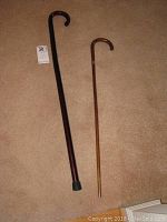 Photo of two walking sticks on carpet showing size difference and curved handles