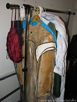 Photo of coats, rainwear, and wedding gown hung on a garment rack