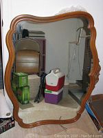 Full front view of large decorative wall mirror showing carved wooden frame and glass surface.