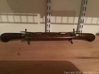 Full view of the carved wood sheath with brass trim, showing detailing on wood and brass fittings