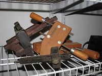 Two Jorgensen adjustable wooden clamps and a vintage wood hand plane on a white wire shelf.
