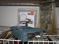 View of two Helping Hands magnifiers with clips in their original plastic packaging, placed on a metal rack