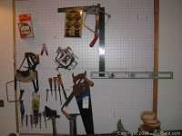 Hand tools on pegboard showing hand saw, chisels, clamps, hammers, and other tools