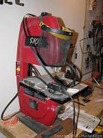 Red Skil benchtop band saw front view showing face shield and cutting table.