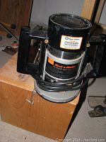 Black and Decker plunge cut router with visible label showing model and warranty info, sitting on wooden box