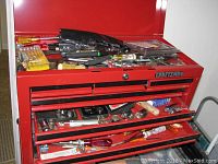 Red Craftsman toolbox top and drawers with assorted tools including ratchets, screwdrivers, and socket sets.