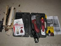 Two oscillating multifunction power tools in red and black color, a hard plastic carrying case, and multiple sanding pad accessories on a flat surface.