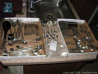 Overview of flatware in three trays showing full assortment of forks, knives, spoons and servers