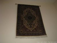 Full view of the White Akbar rug hung on a wall showing the entire design and fringe.