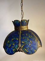 Full view of hanging blue slag glass and brass fixture with chain