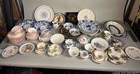 Full lot overview on tabletop, showing plates, bowls, teacups, sugar, creamer