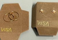 Hoop and star pearl earrings displayed on brown holders