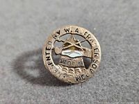 Front view of circular 10K gold Woodmen of the World lapel pin showing full inscription and enamel emblem