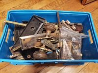 Blue tote filled with assorted antique door hardware pieces