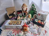 Overview of lot showing Lladro bell, Carousel unicorn bells, Jasco bells, ANRI bells, cast-iron sled figurine, nutcracker, crystal heart ornament and linens