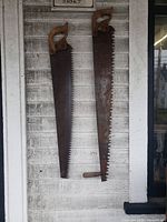 Both hand saws hanging side by side on wall