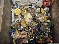 Drawer filled with assorted jewelry, buttons, watch, medals